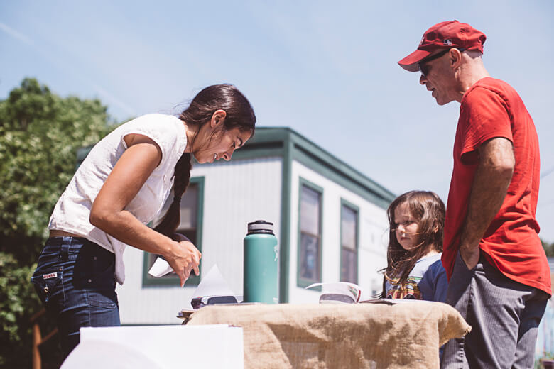 Family gathered around table with thermos on sunny day outdoors