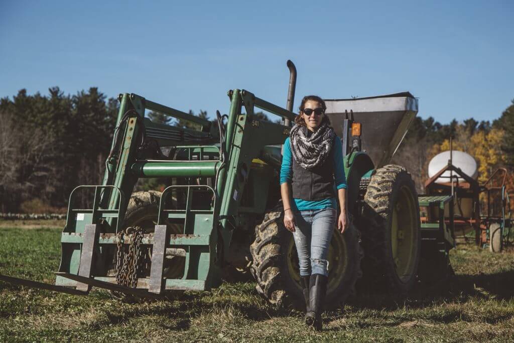 Farmer standing next to large green tractor on rural farm field