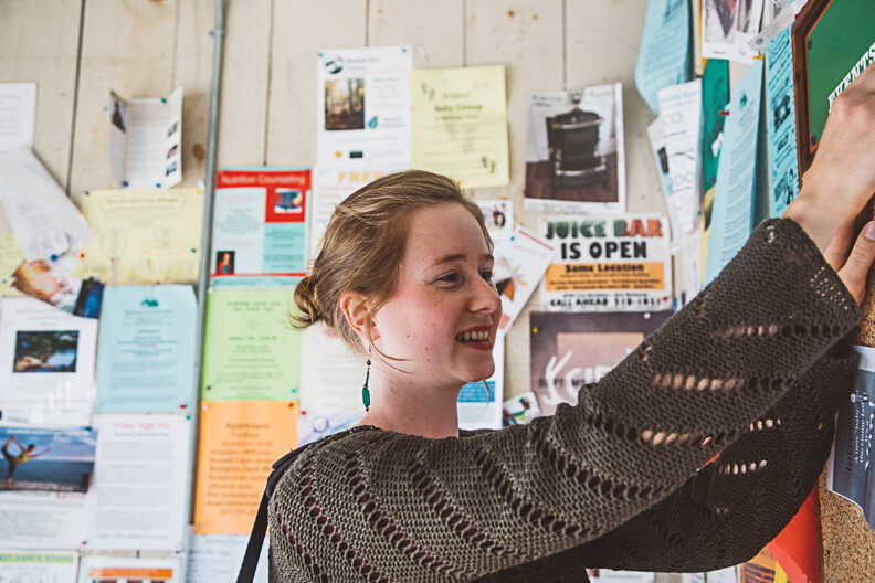 Smiling person in knit sweater adjusting poster on bulletin board