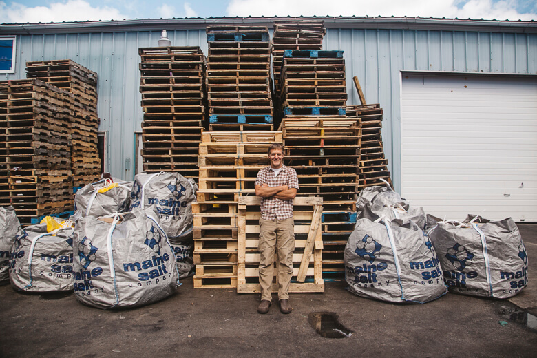 Worker standing in front of stacked wooden pallets and large storage bags