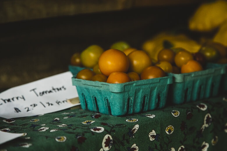 Ripe cherry tomatoes in teal basket on patterned green cloth