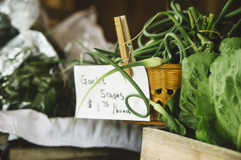 Garlic scapes in basket with handwritten price tag and clothespin