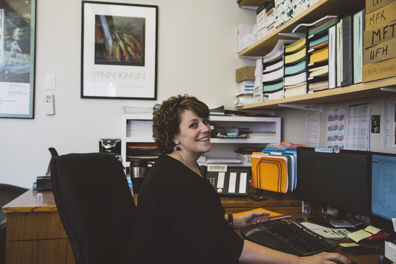Smiling professional working at desk in organized office with framed artwork