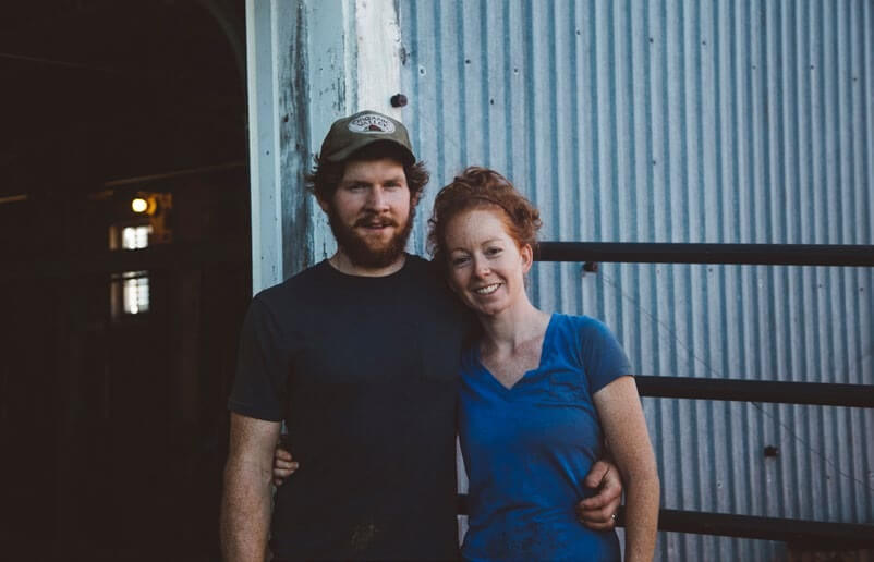 Smiling couple embracing in front of blue metal wall