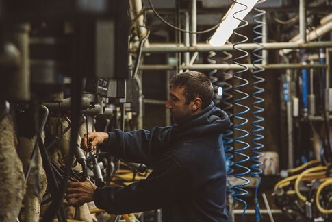 Industrial worker adjusting machinery in dimly lit factory workshop