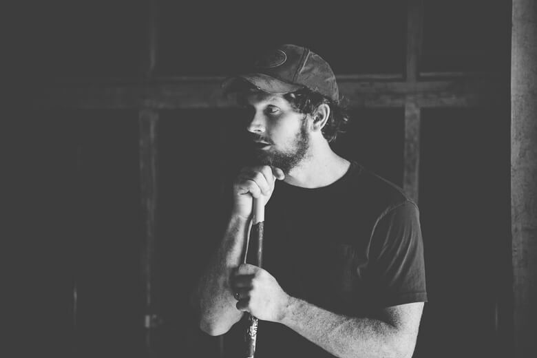Person in cap holding microphone, looking thoughtful in black and white