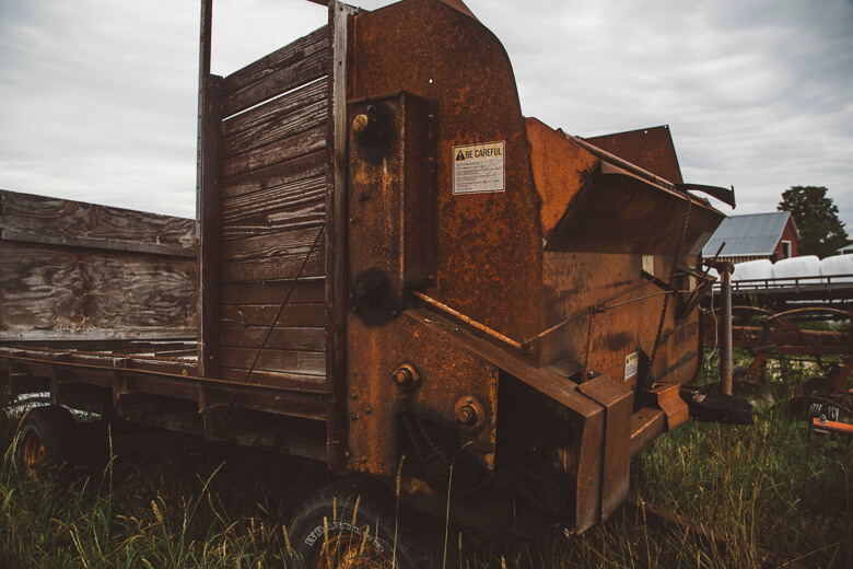 Rusty old agricultural machinery in grassy field with overcast sky