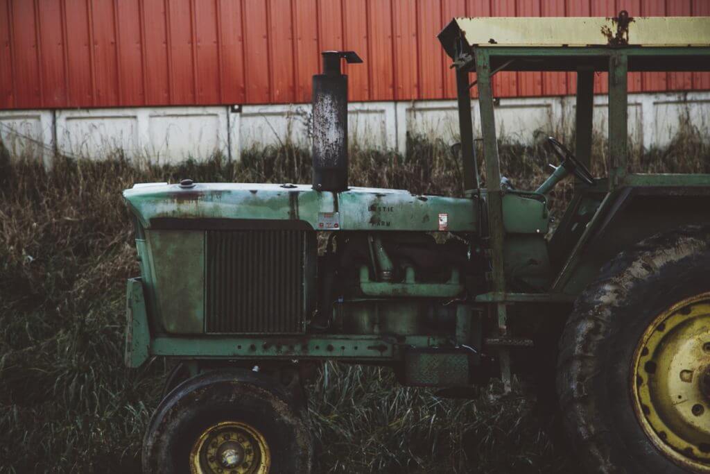 A green tractor parked in front of a red building