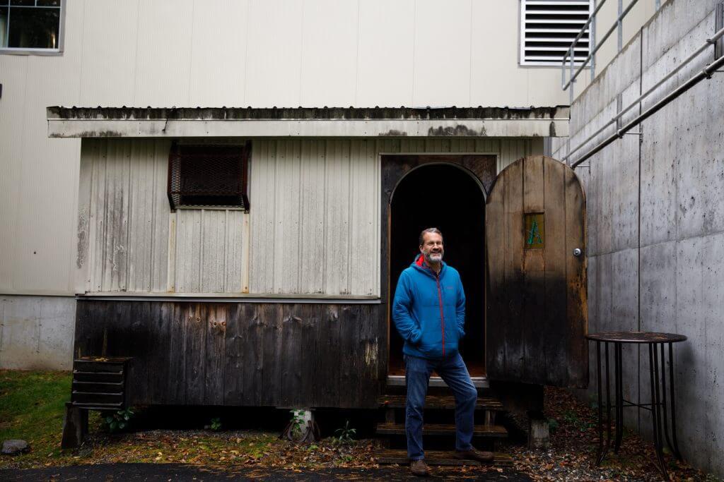 Person in blue jacket standing in doorway of weathered wooden building