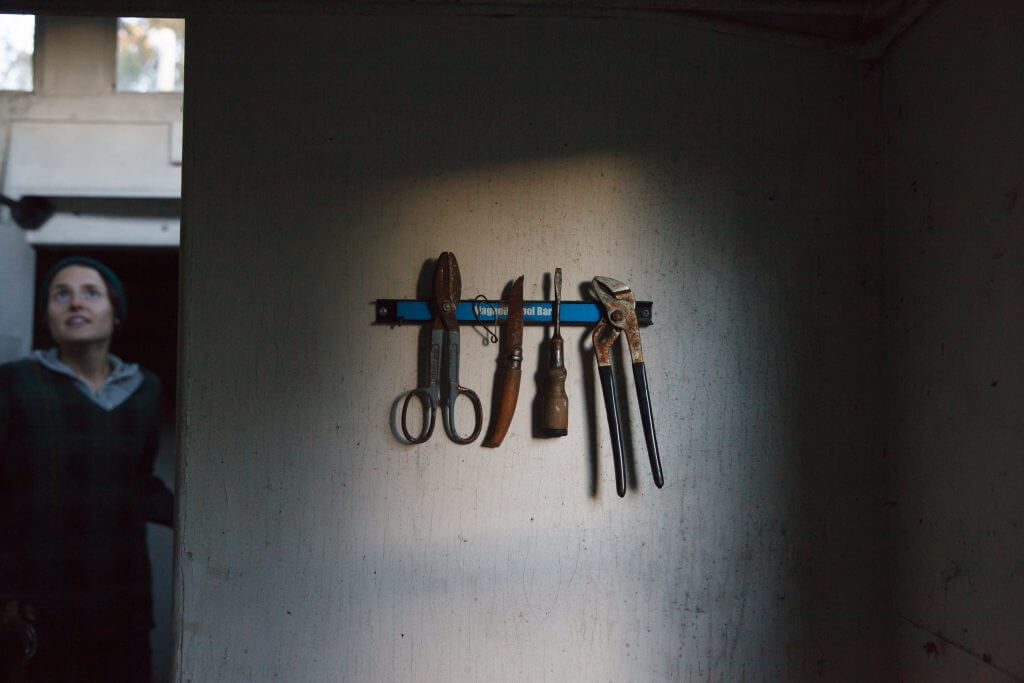 Vintage tools hanging on a blue magnetic bar against a dim wall