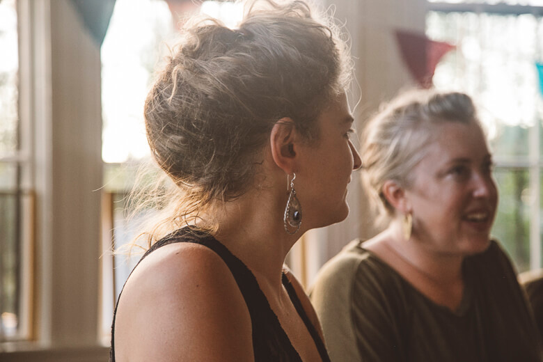 Two women in conversation, one in profile with earrings, soft lighting
