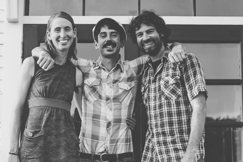Three friends smiling and posing together in black and white photo