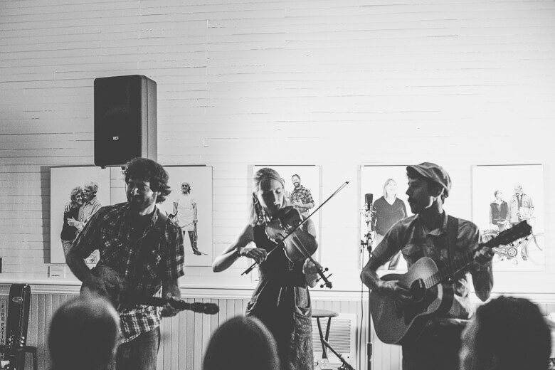 Black and white image of three musicians performing with guitar and violin