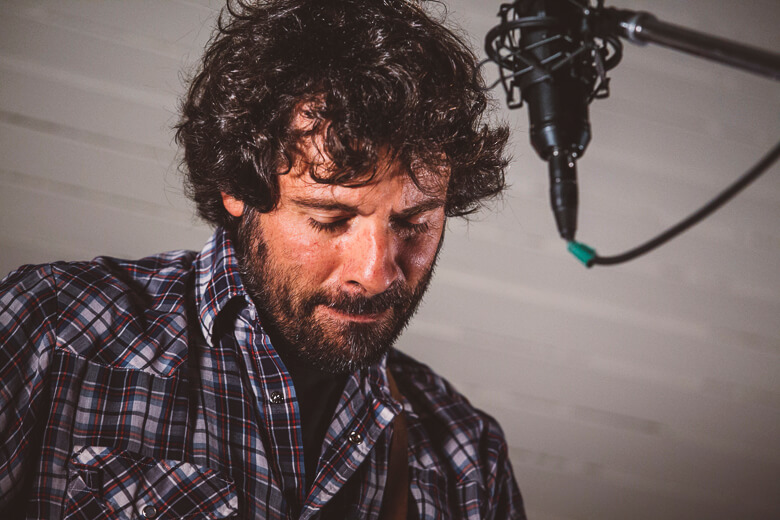 Musician with curly hair recording in studio with professional microphone