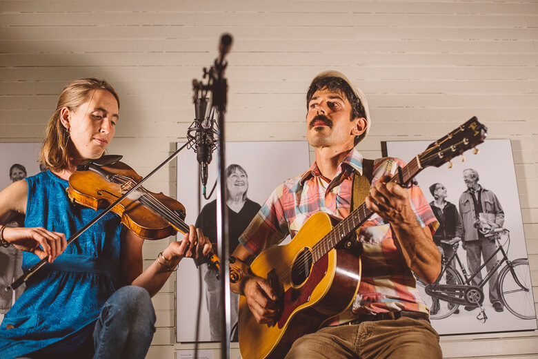 Musicians playing violin and acoustic guitar near vintage photo backdrop