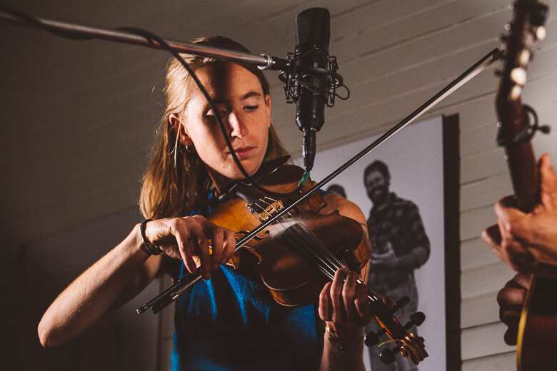 Musician playing violin in recording studio with professional microphone