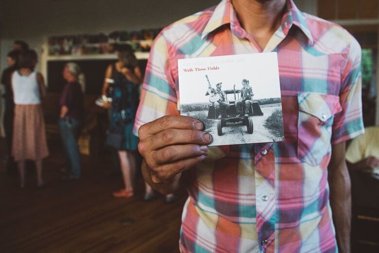 Person in plaid shirt holding vintage black and white photo of tractor