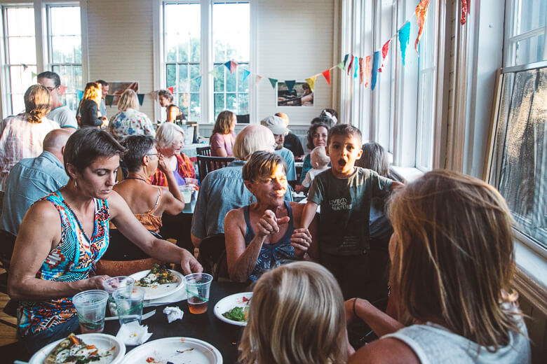 Diverse group enjoying meal together in bright, festive dining room with bunting