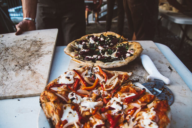Two artisan pizzas with unique toppings on a marble countertop