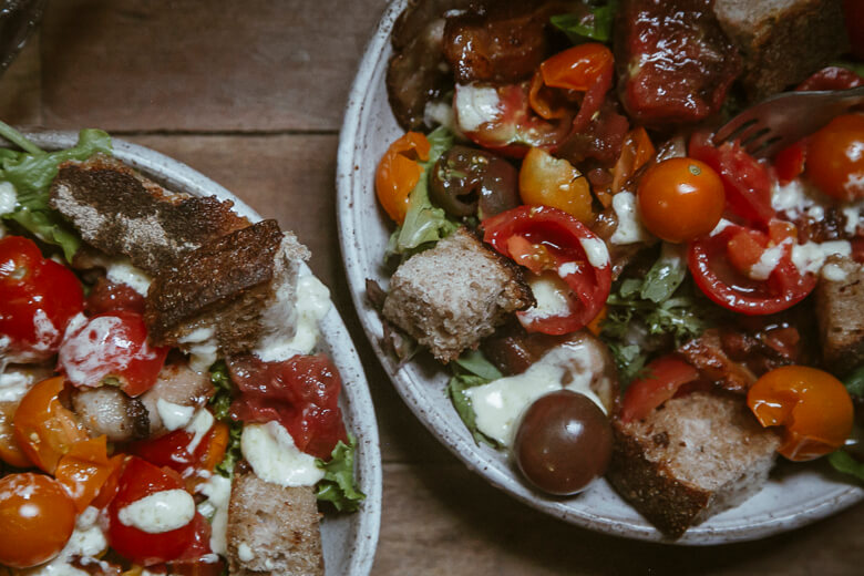 Rustic salad with colorful tomatoes, bread chunks, and creamy white cheese