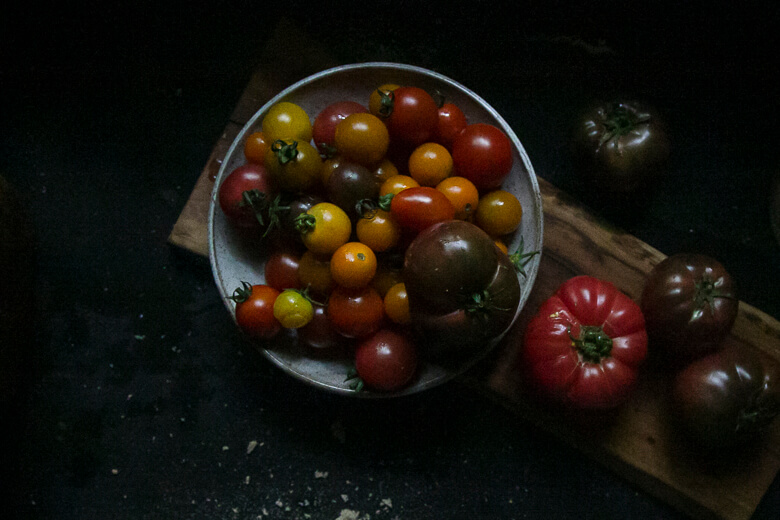 Colorful heirloom tomatoes in a rustic bowl on dark wooden surface