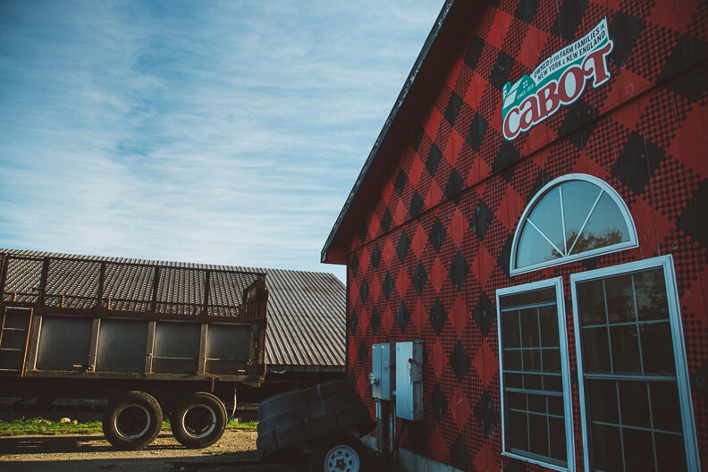 Red plaid Cabot building with trailer and farm equipment outside