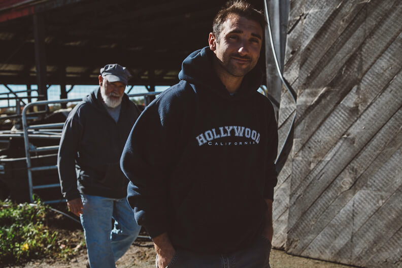 Two men in hoodies standing near wooden wall outdoors