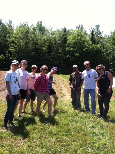 Group of people standing on grassy path with trees in background
