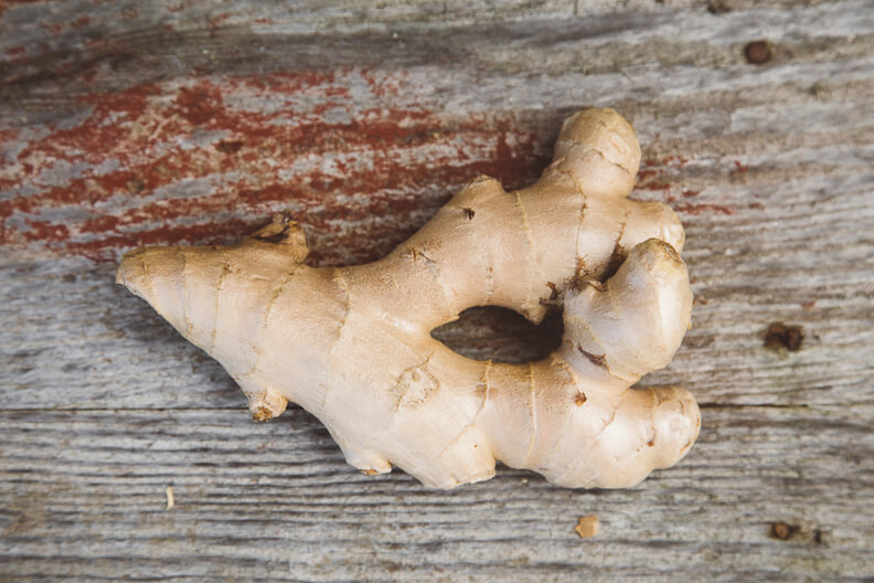 Fresh ginger root with knobby texture on weathered wooden background