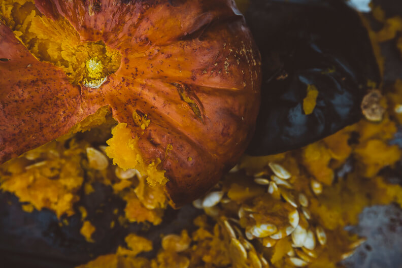 Ripe orange pumpkin with autumn leaves and seeds in warm tones