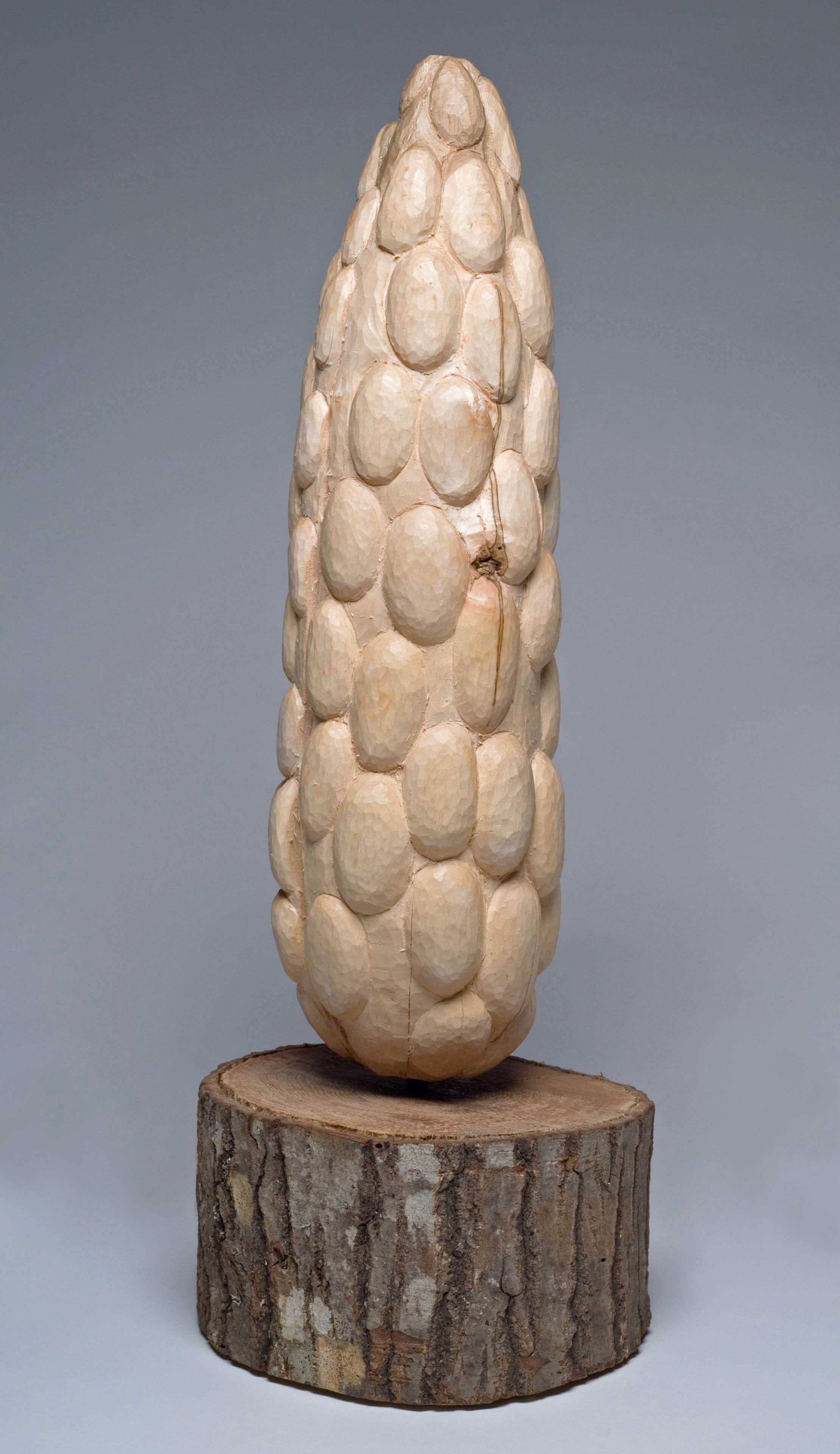 Carved stone sculpture of elongated oval shapes on wooden base