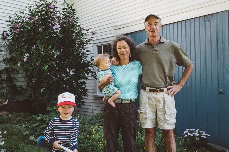 Grandparents smiling with two grandchildren outside their home