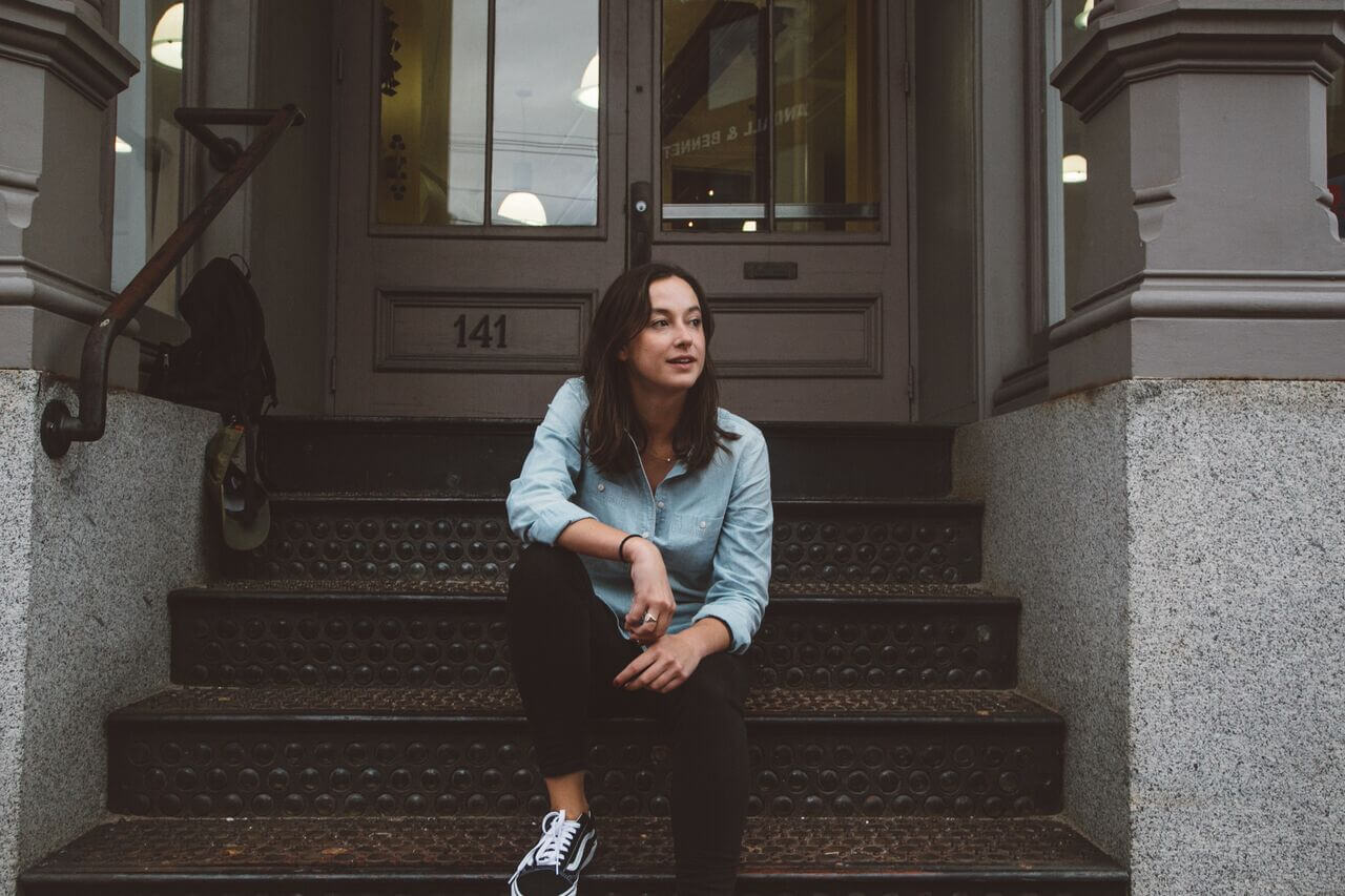 Woman sitting on textured steps in front of house number 141