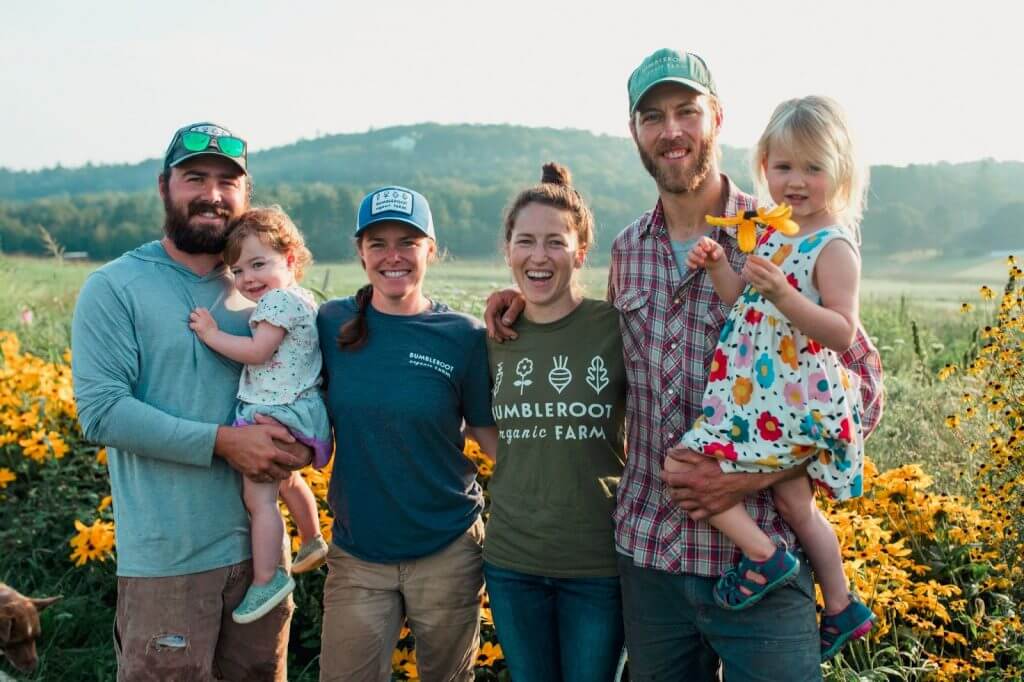 Bumbleroot Organic Farm team with children standing in a field of yellow flowers