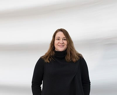 Woman in black sweater smiling against soft gray background