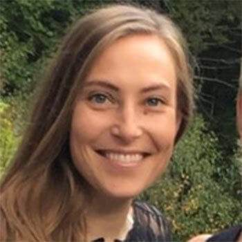 Smiling woman with long hair in front of green leafy background