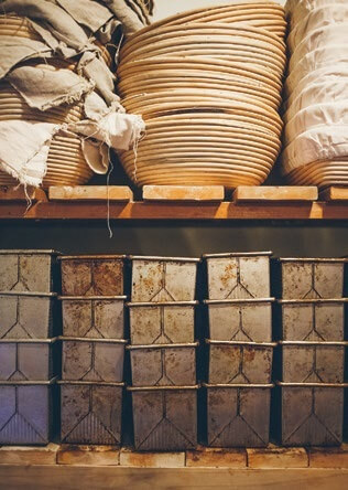 Stacked ceramic bowls and textured storage boxes on rustic wooden shelves