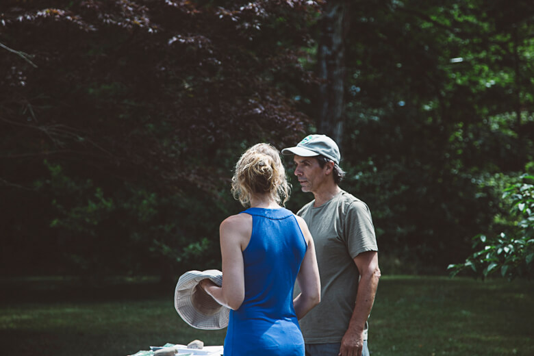 Two people talking in a lush green garden or backyard setting