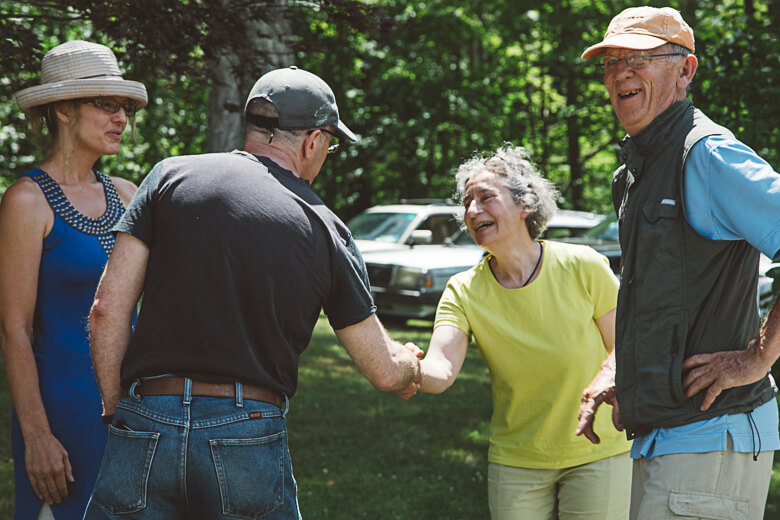 Senior friends meeting outdoors, shaking hands and smiling in a park