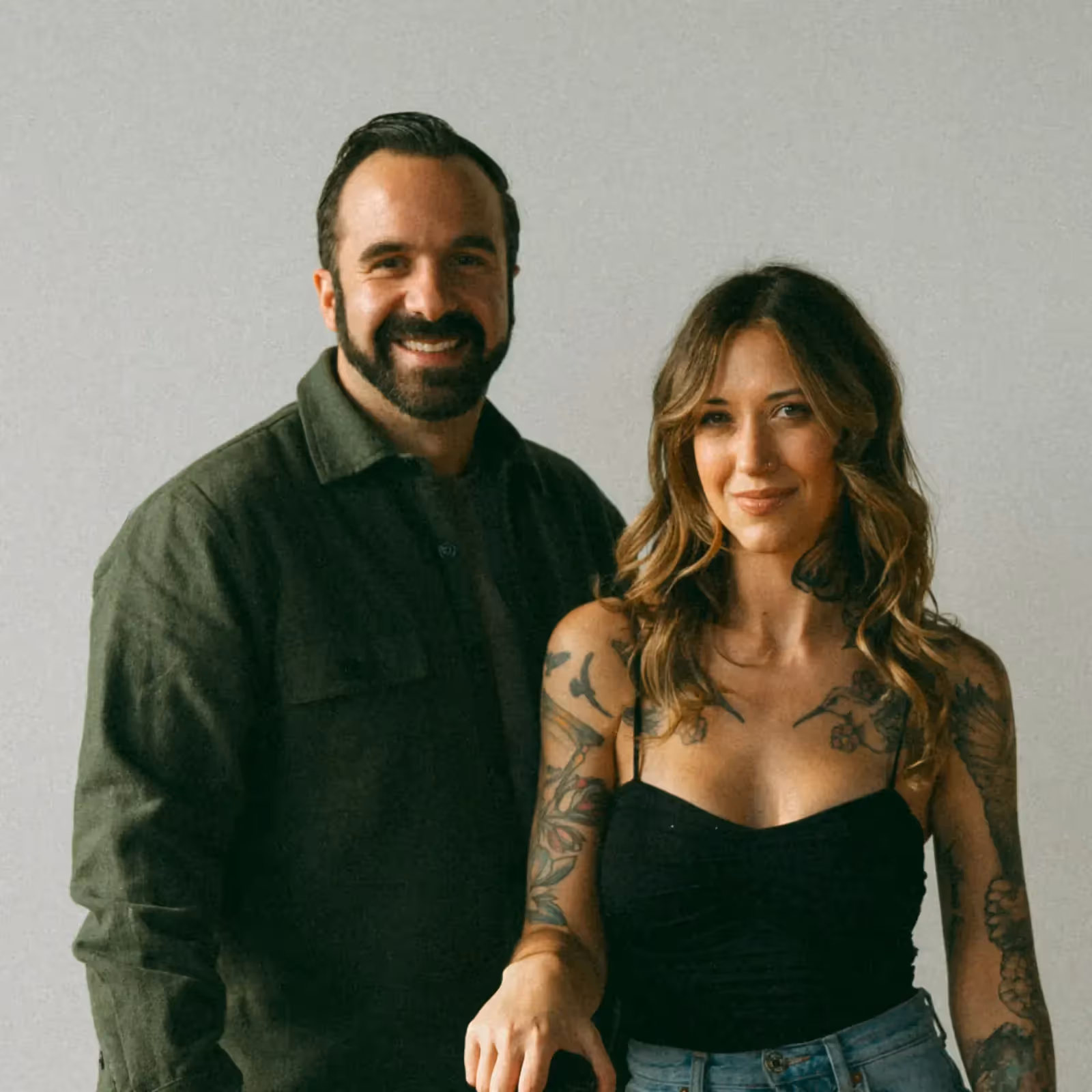 Portrait of a smiling man and woman with tattoos standing together.