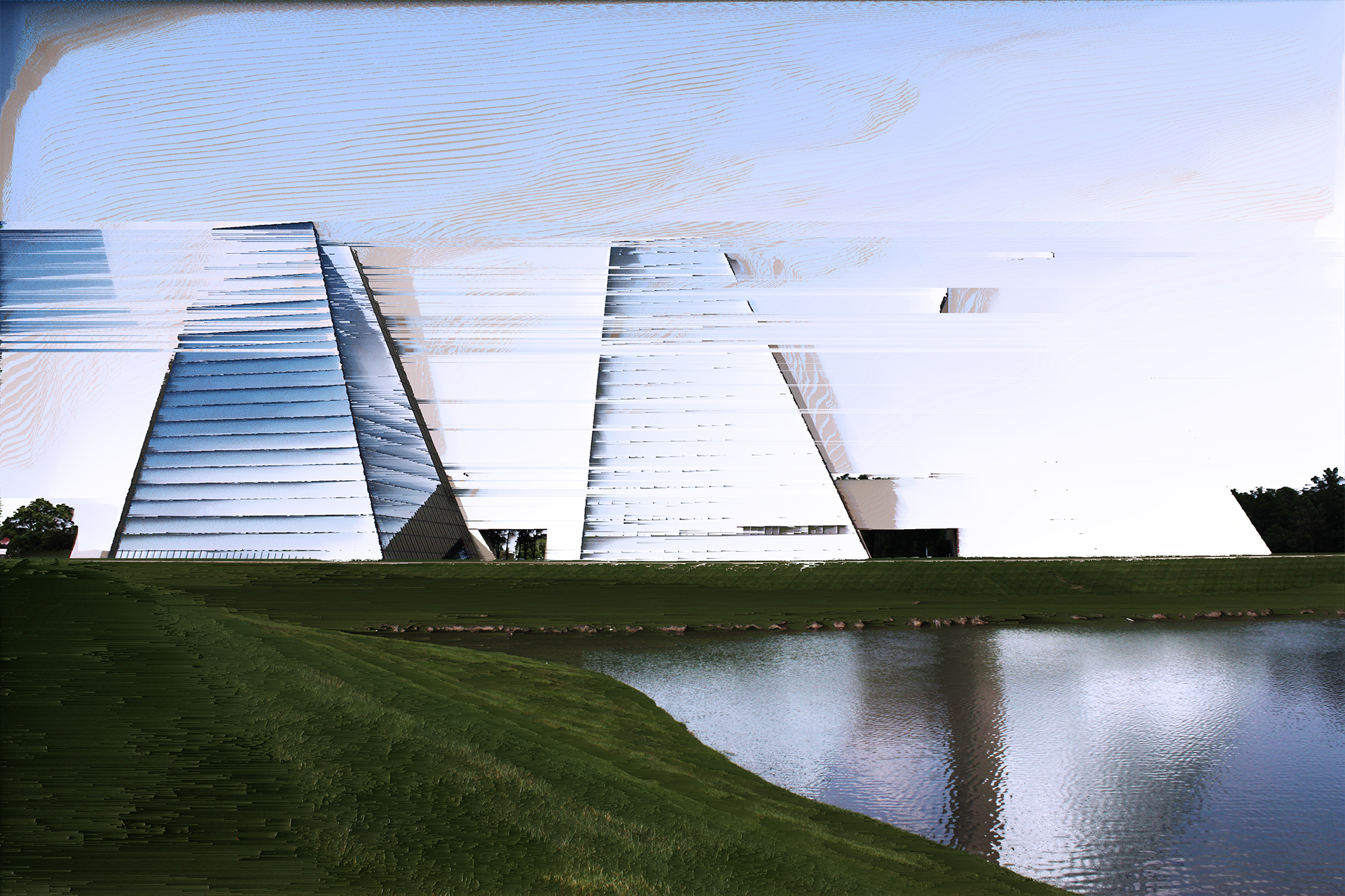 Glitch art of angular white buildings beside a grassy pond, with the sky and walls stretched into horizontal streaks