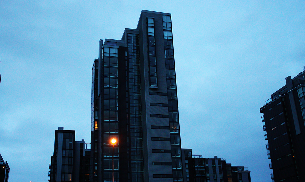 High-rise apartment towers against a blue dusk sky, with a single streetlight glowing at the base