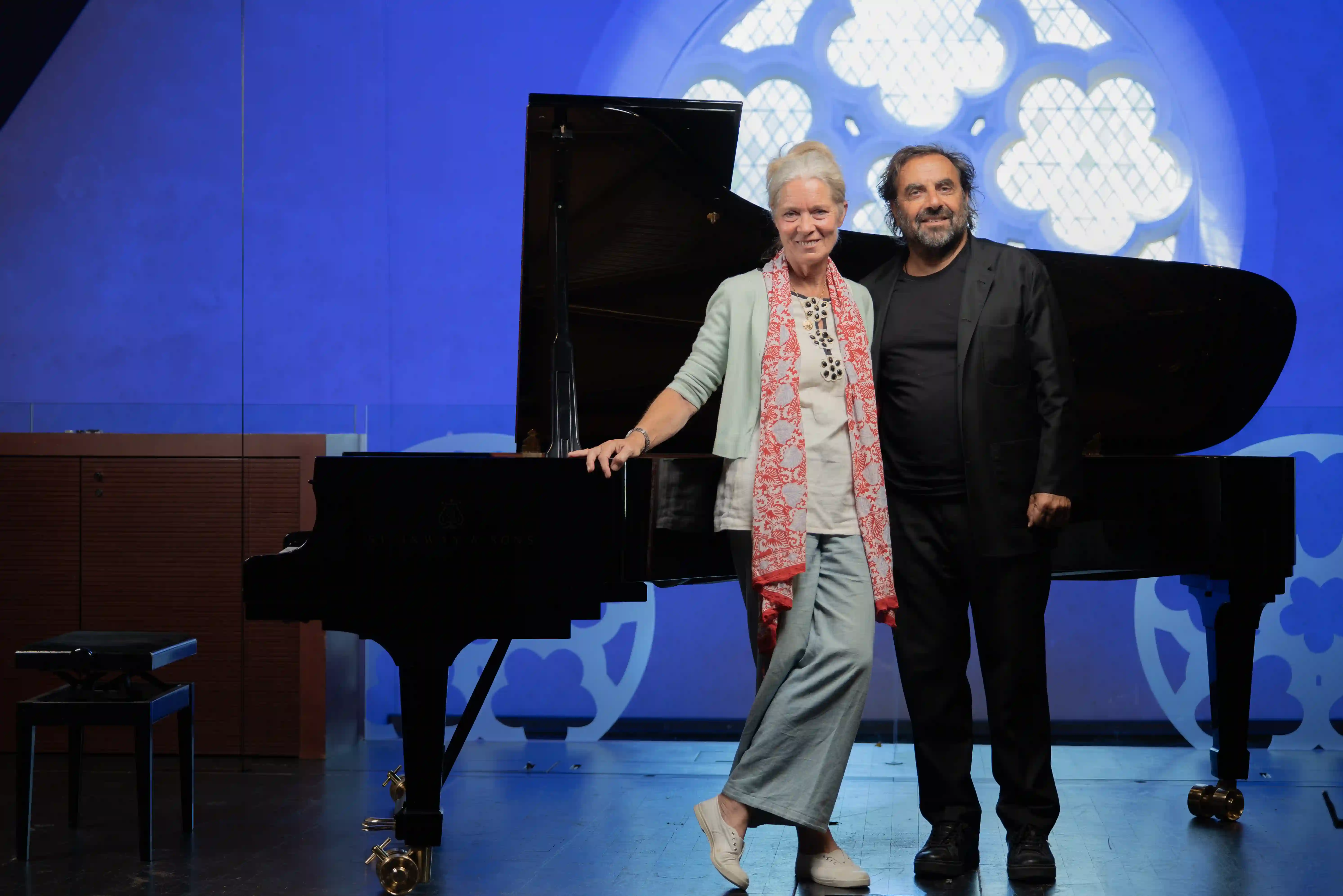 André Manoukian et une femme posant devant un piano à queue