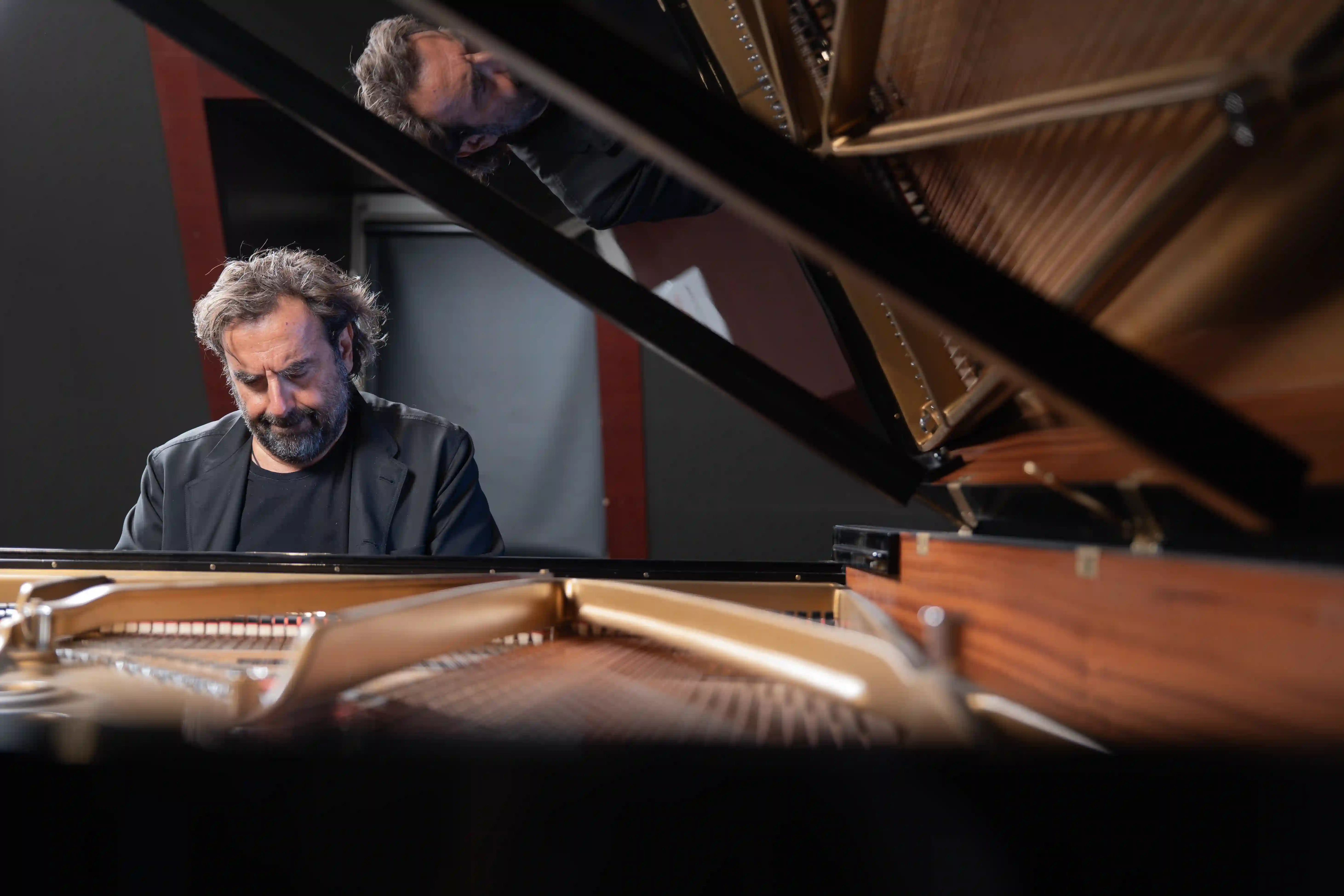 André Manoukian au piano, son reflet dans le couvercle de l’instrument