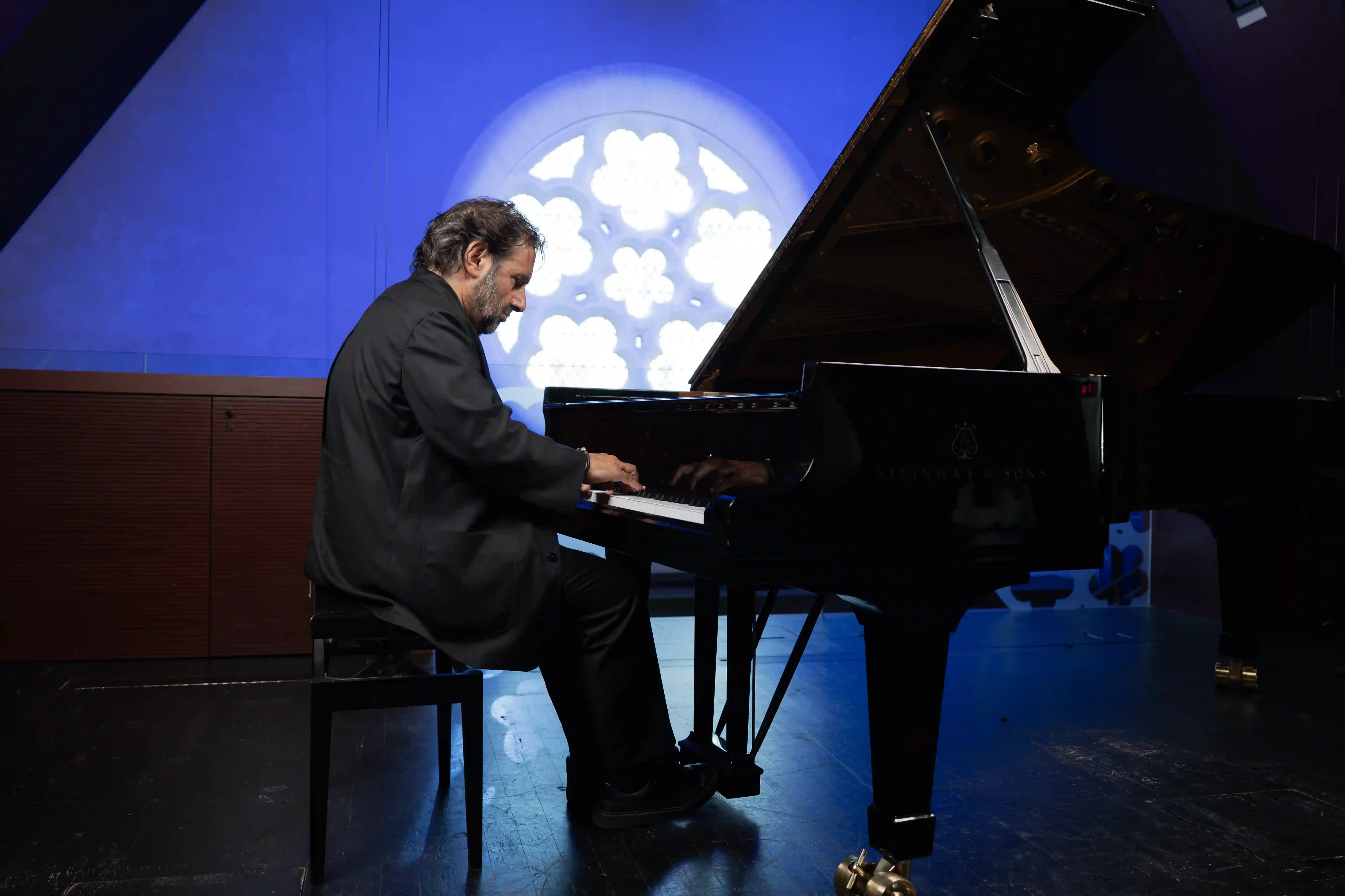 André Manoukian jouant du piano devant la rosace projetée