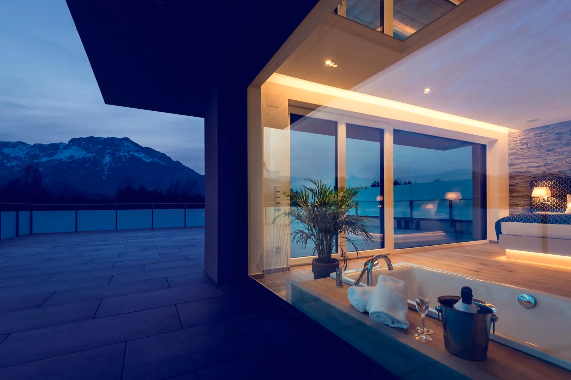 Dachterrasse mit Blick ins Penthouse eines Hotels, freistehender Badewanne und Sonnenuntergang am Untersberg bei Salzburg