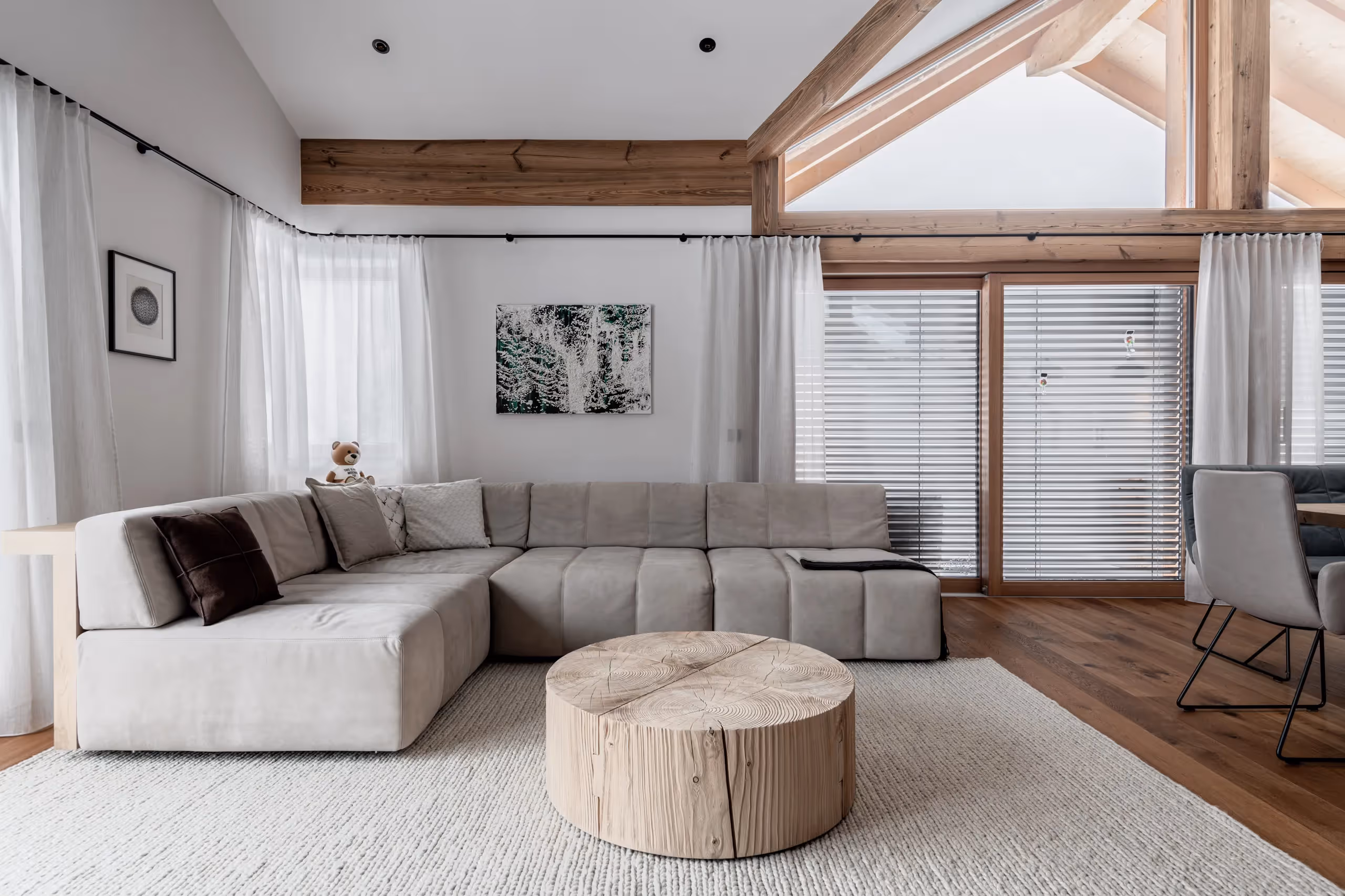 Wohnbereich mit Sofa und Esstisch, großen weißem Teppich und rustikalem Chalet-Haus