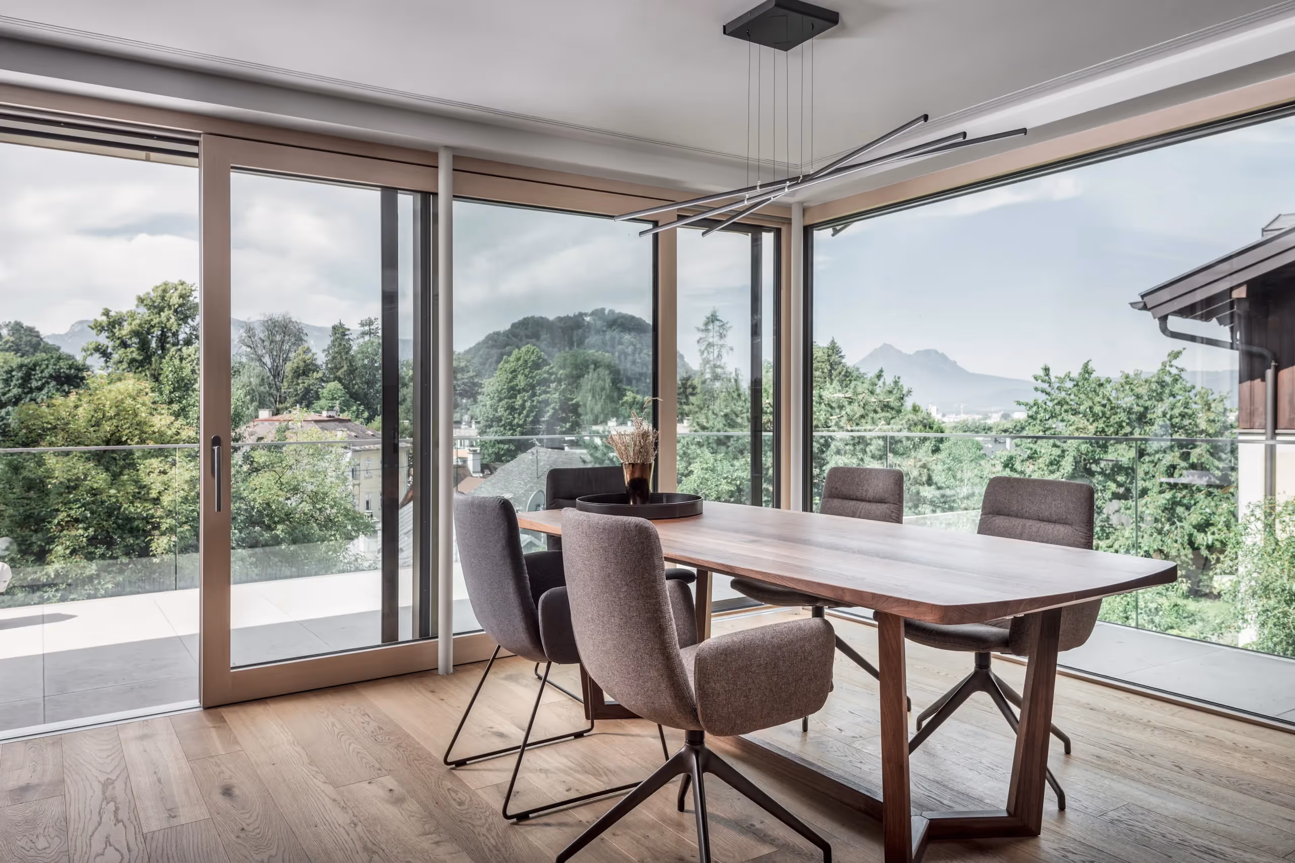 Esstisch aus Holz mit großen Panoramafenstern und Blick auf Salzburg