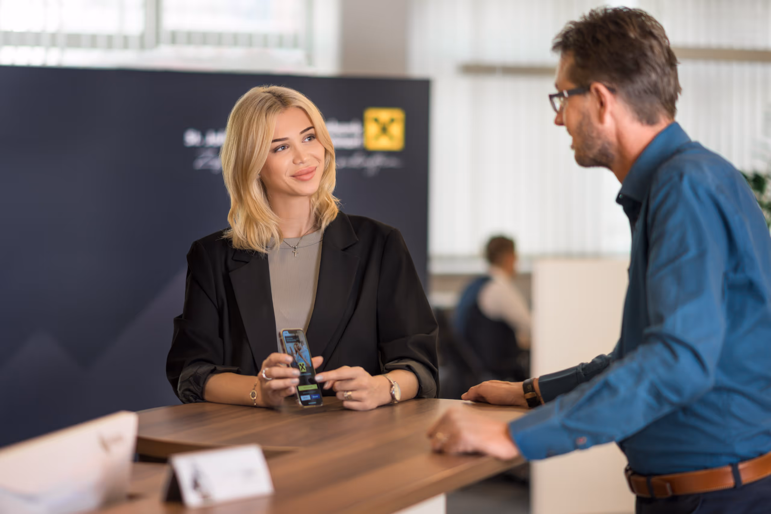 Imagefoto für die Raiffeisenbank – Kundengespräch am Bankschalter mit Fokus auf ELBA-Banking App