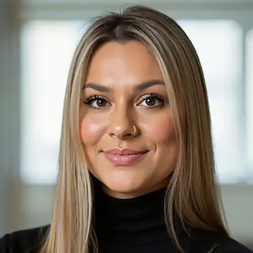 Portrait of a smiling woman with long blonde hair, wearing a black turtleneck and a nose ring.